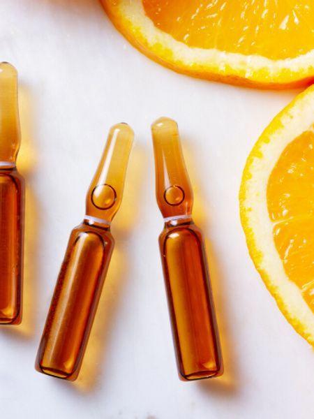 Vitamin C injection being prepared in a clinical setting with a bright orange backdrop symbolising citrus health benefits.